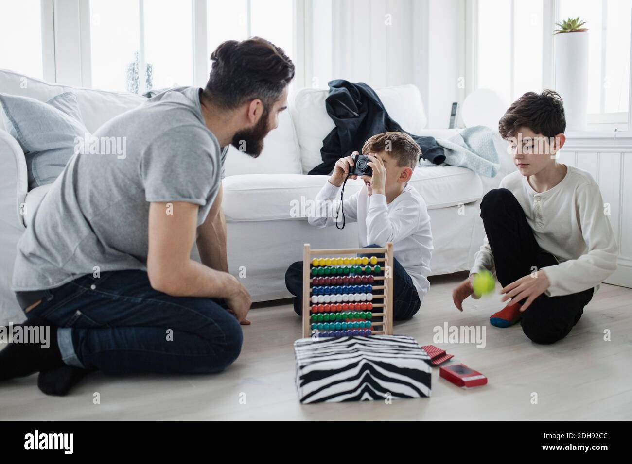 Garçon photographiant le père par frère jouant avec le ballon dans la vie chambre à la maison Banque D'Images