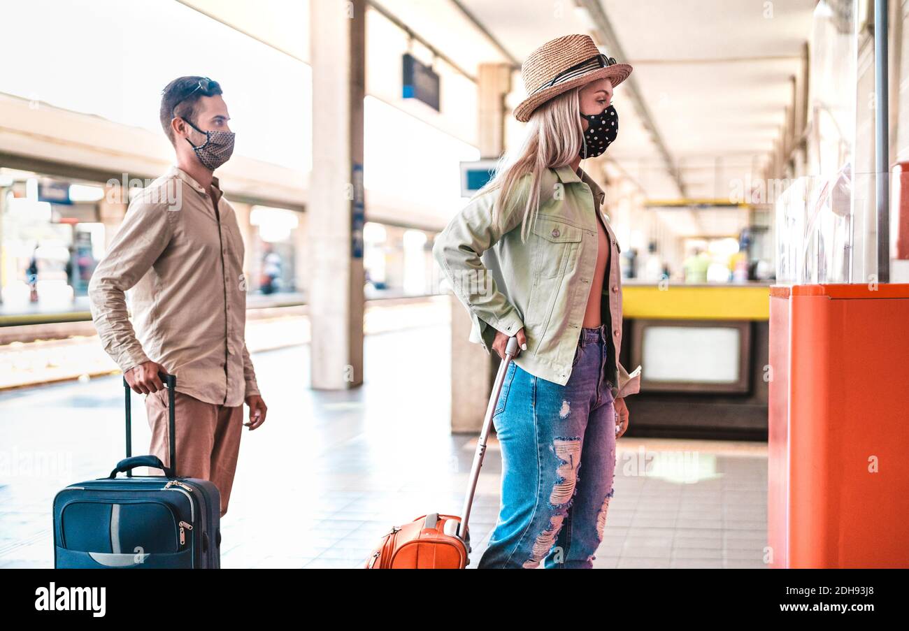 Jeune couple en file d'attente pratiquant la distanciation sociale au train Station - Nouveau concept de voyage normal avec des personnes avec le visage masque sur file d'attente au bureau inf Banque D'Images Jeune couple en file d'attente pratiquant la distanciation sociale au train Station - Nouveau concept de voyage normal avec des personnes avec le visage masque sur file d'attente au bureau inf Banque D'Images