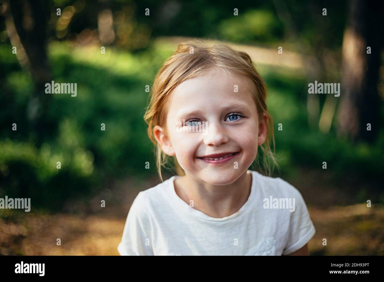 Portrait d'une jolie fille souriante debout en forêt Banque D'Images