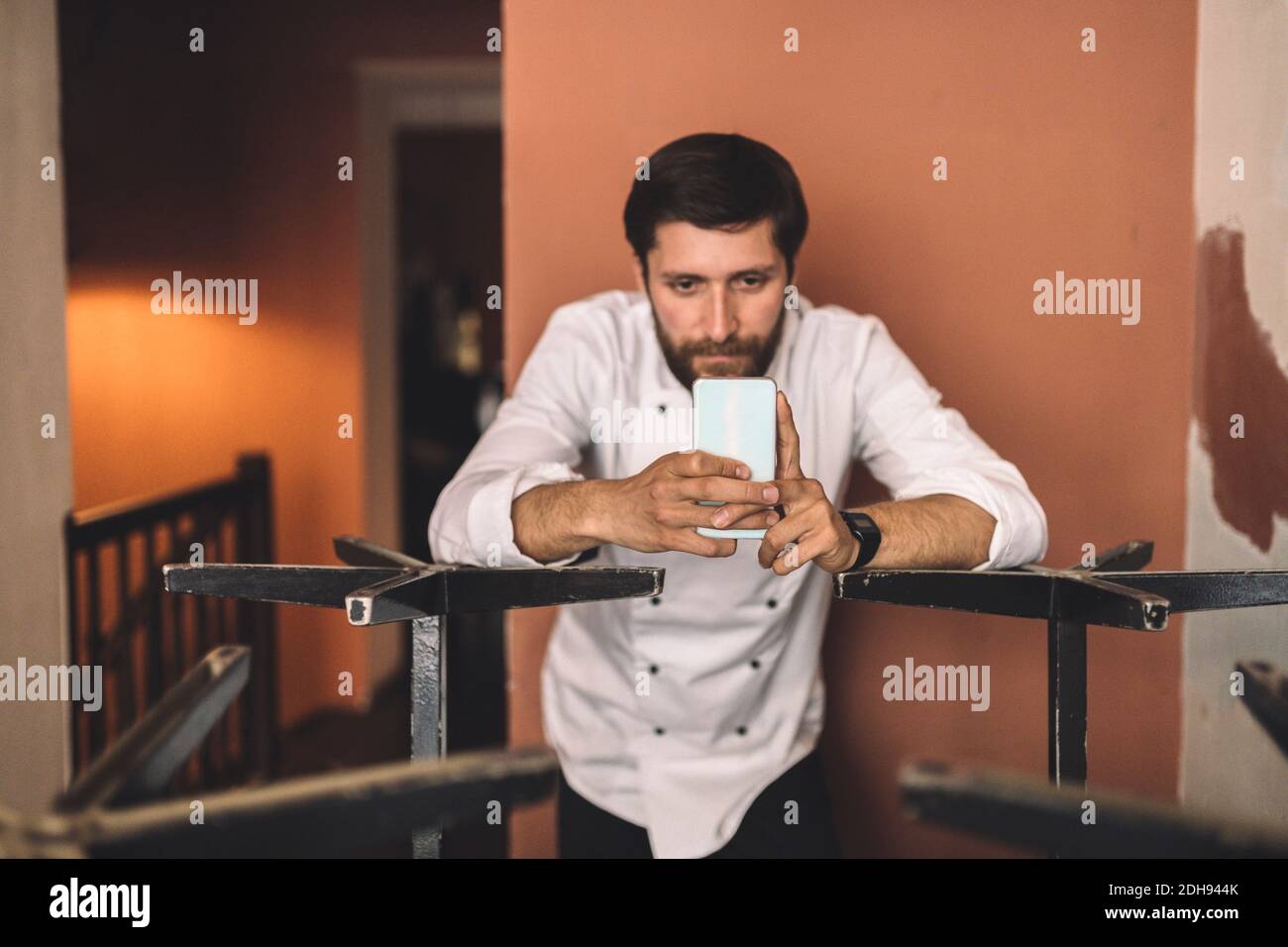 Chef masculin utilisant un téléphone intelligent dans le restaurant Banque D'Images