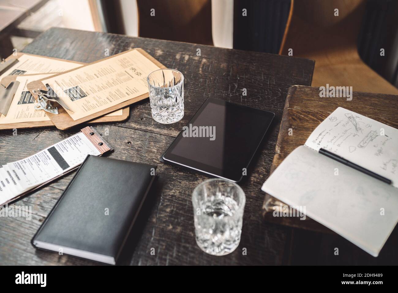 Vue en grand angle du verre à boire avec agenda et numérique tablette sur table au restaurant Banque D'Images