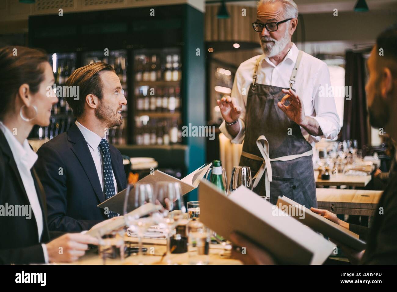 Un serveur parle aux gens d'affaires dans un restaurant Banque D'Images