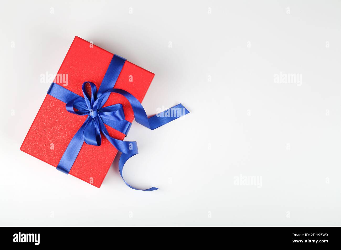boîte cadeau ou cadeau rouge avec ruban bleu sur fond blanc. composition pour anniversaire, saint-valentin, fête des mères ou mariage. vue du dessus espace pour les copies Banque D'Images boîte cadeau ou cadeau rouge avec ruban bleu sur fond blanc. composition pour anniversaire, saint-valentin, fête des mères ou mariage. vue du dessus espace pour les copies Banque D'Images
