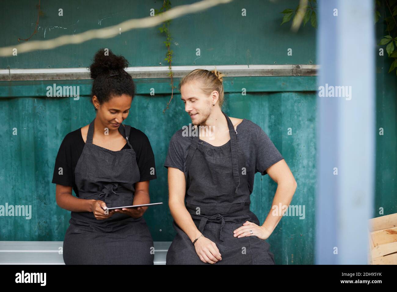 Jardiniers avec tablette numérique assis sur un banc dans la cour Banque D'Images