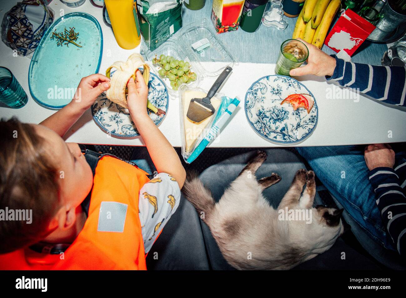 Vue en grand angle du père buvant pendant que le fils mangeait de la banane à la table Banque D'Images