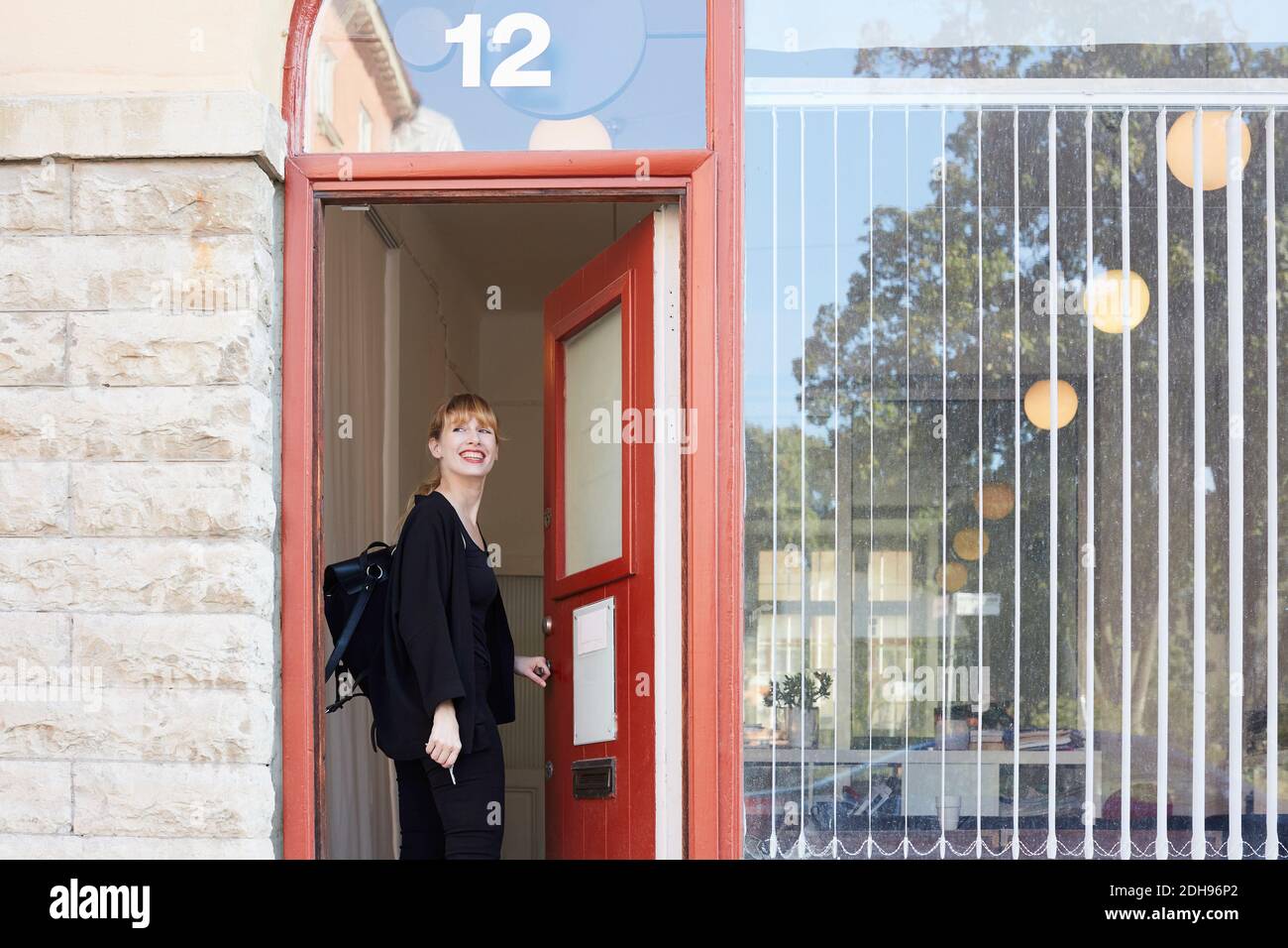 Femme d'affaires de taille moyenne souriante debout à l'entrée du bureau Banque D'Images