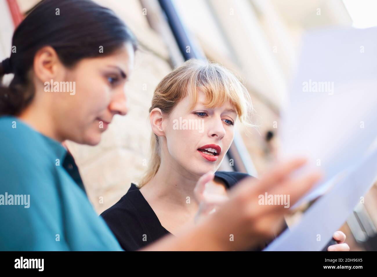 Les femmes d'affaires de taille moyenne discutent de documents à l'extérieur du bureau Banque D'Images
