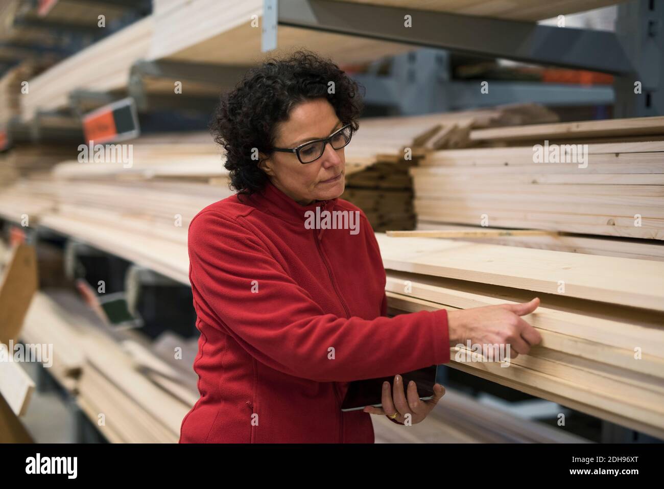 Client féminin qui choisit une planche en bois dans un magasin de quincaillerie Banque D'Images