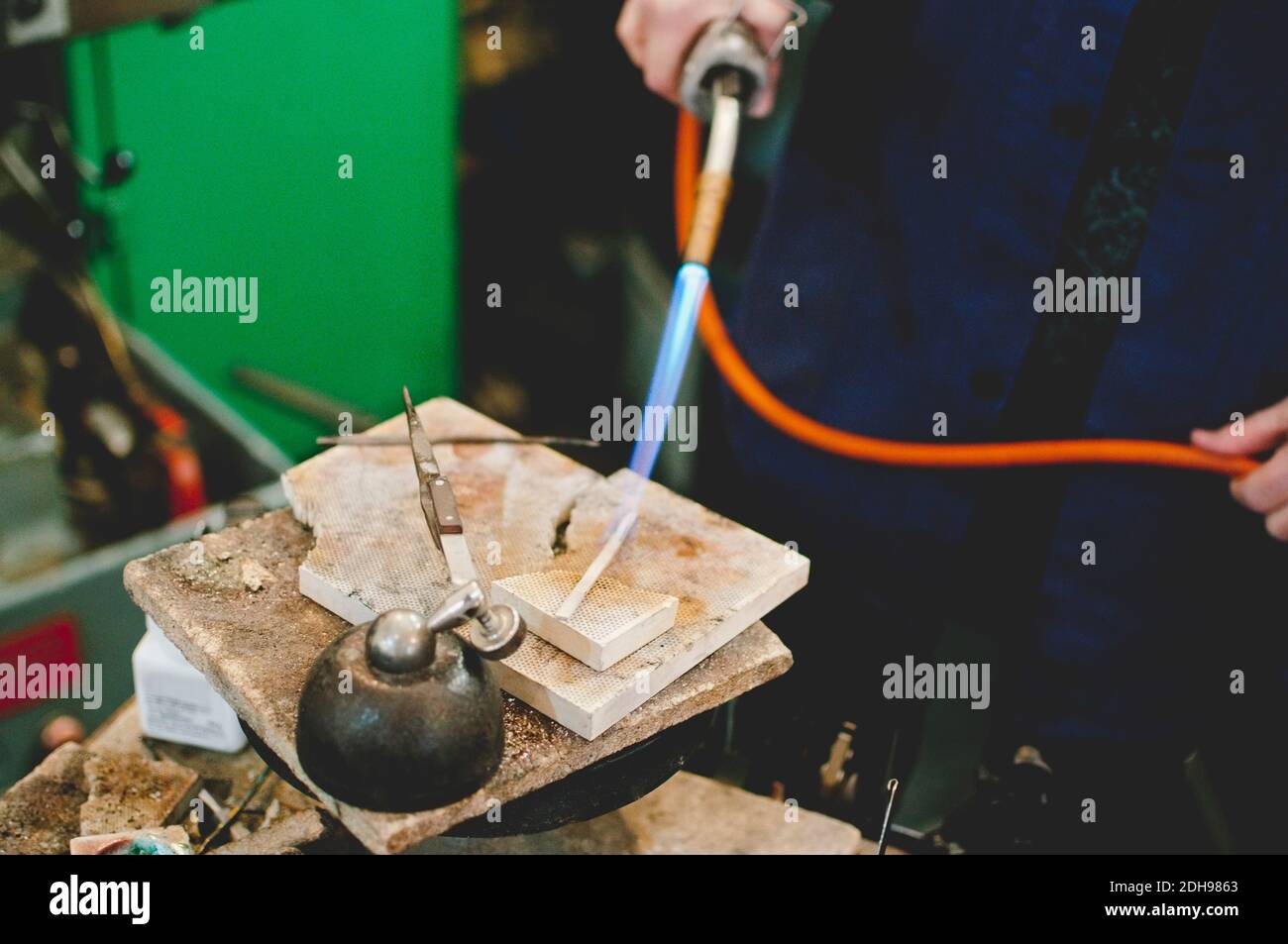 Section médiane de l'artisan principal utilisant un chalumeau pour le travail des métaux dans les bijoux atelier Banque D'Images