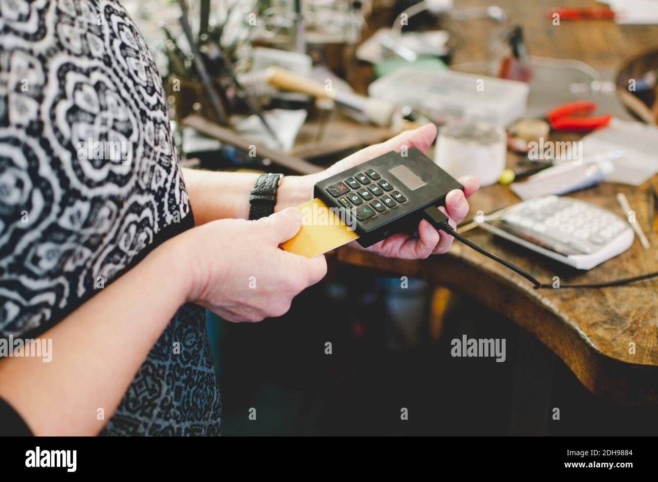 Section médiane de la femme âgée utilisant le lecteur de carte de crédit dans les bijoux atelier Banque D'Images