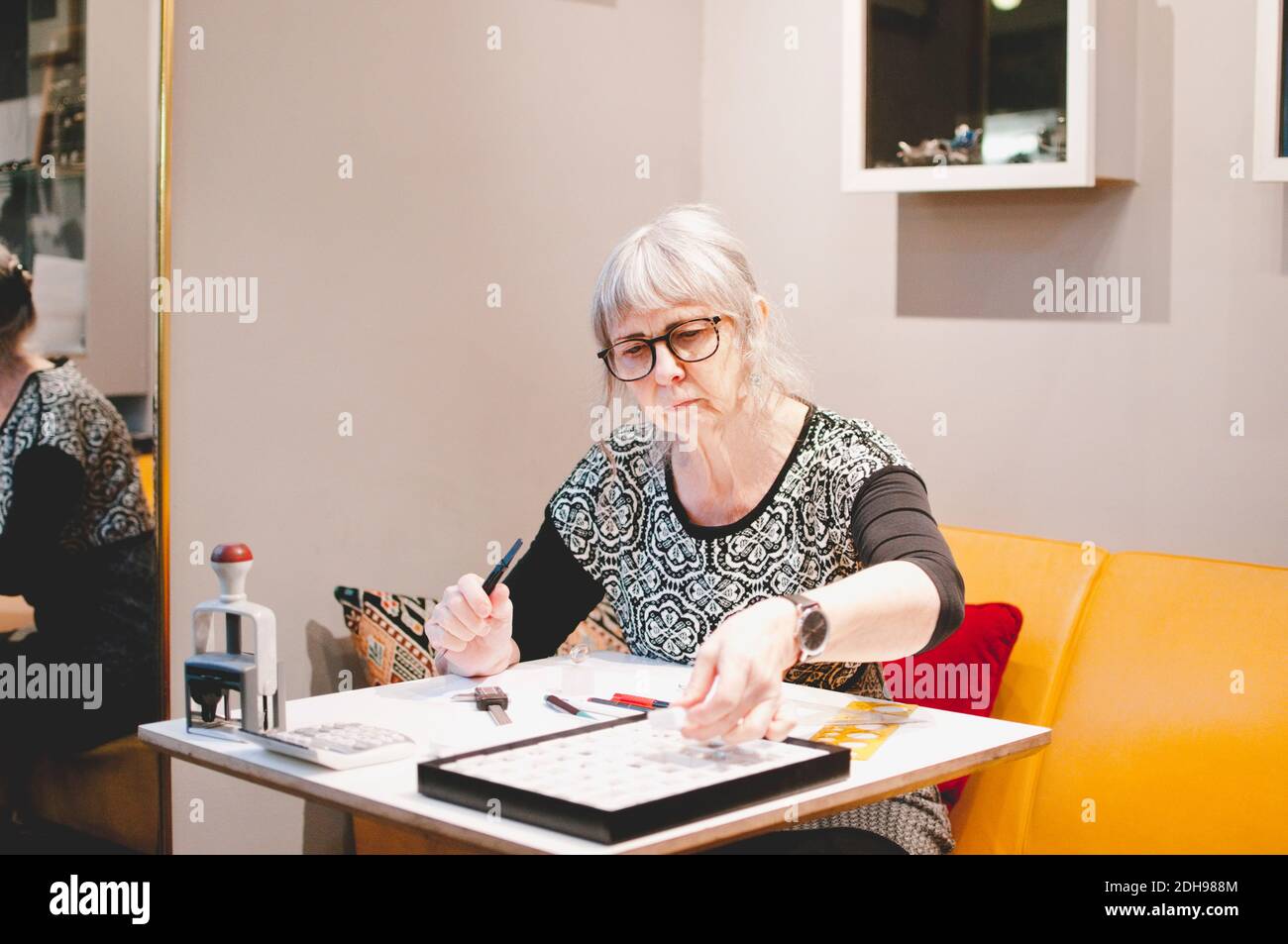 Bijoutier femme senior qui fait des bijoux au bureau dans l'atelier Banque D'Images