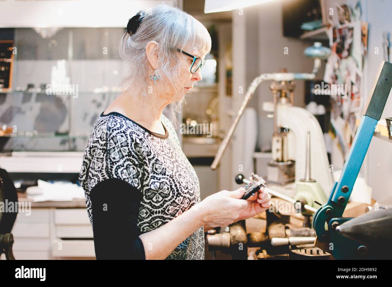 Vue latérale d'une femme âgée utilisant un étrier dans un atelier de bijoux Banque D'Images