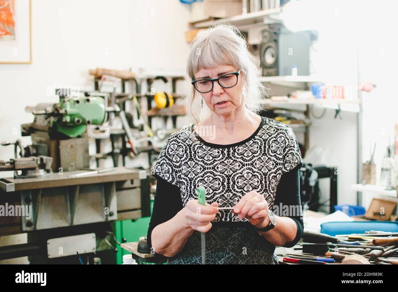 Femme senior tenant un outil de travail dans un atelier de bijoux Banque D'Images