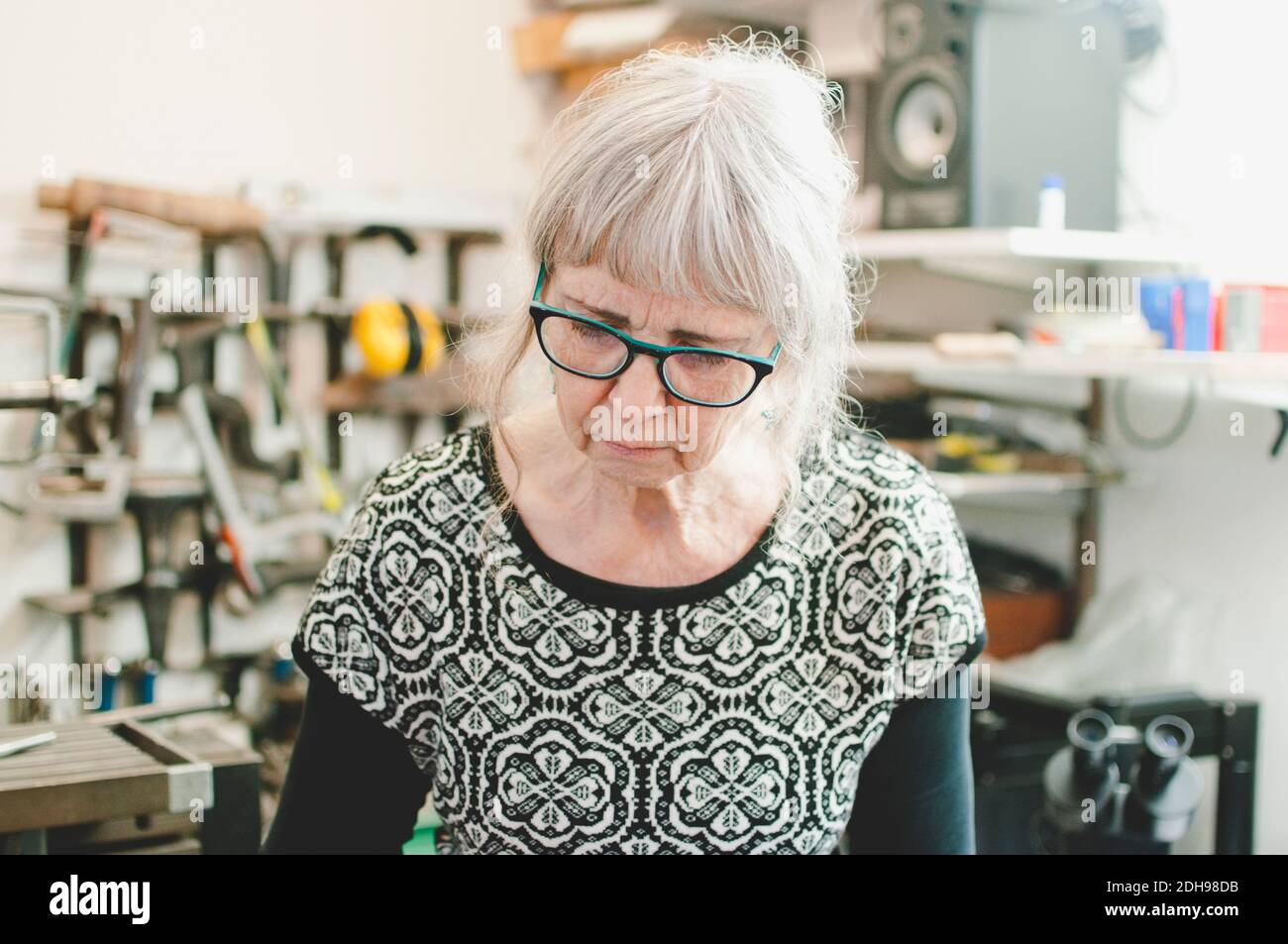 Femme âgée portant des lunettes lorsqu'elle travaille dans un atelier de bijoux Banque D'Images