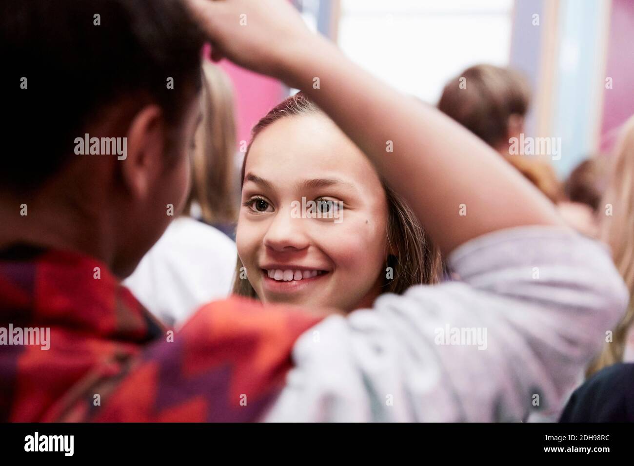 Fille souriante regardant une amie de sexe féminin à l'école moyenne Banque D'Images