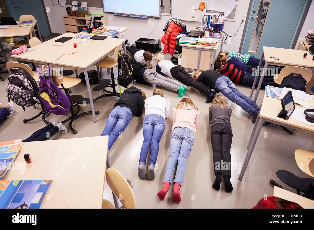 Vue en grand angle des élèves de premier cycle en position de planche en classe Banque D'Images
