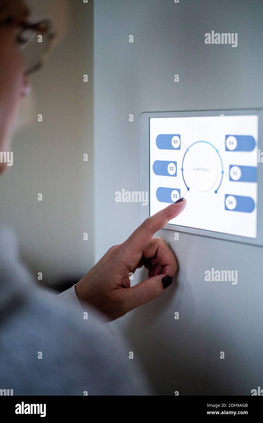 Femme utilisant une tablette numérique au mur dans une maison moderne Banque D'Images