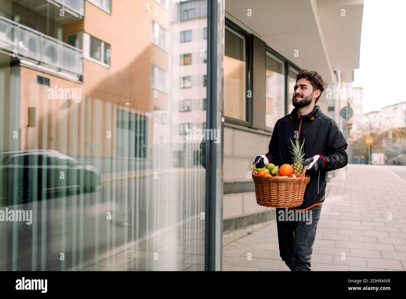Jeune homme livrant un panier de fruits dans le bâtiment Banque D'Images