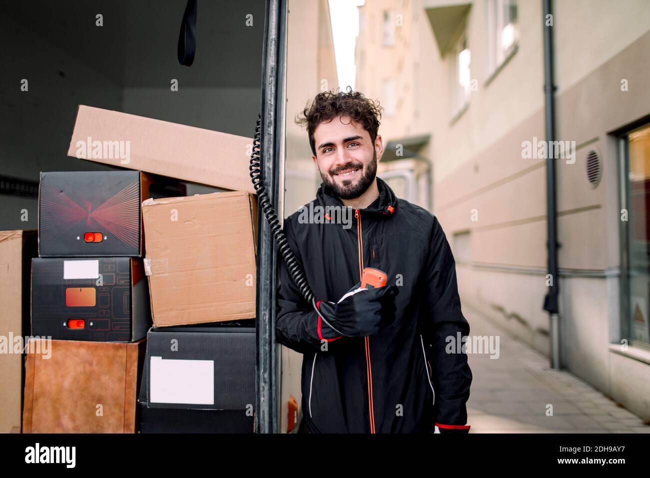 Portrait d'un liveur confiant avec des boîtes dans un camion Banque D'Images