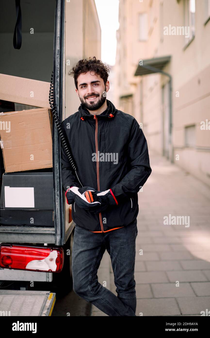Portrait d'un jeune liveur confiant avec des boîtes dans un camion Banque D'Images