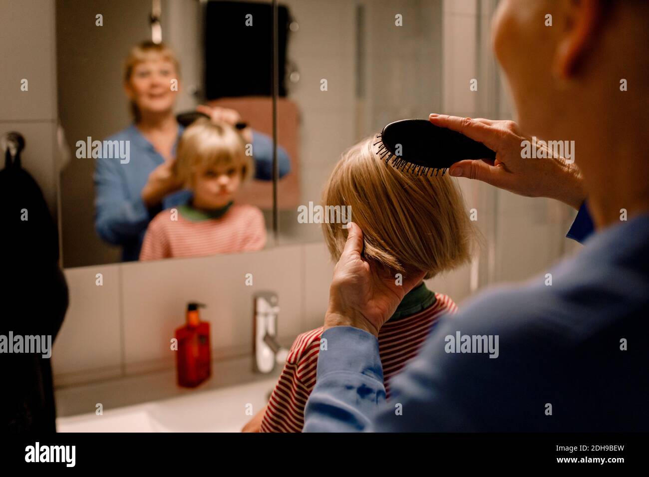 Grand-mère peignant les cheveux de petit-fils dans la salle de bains à la maison Banque D'Images