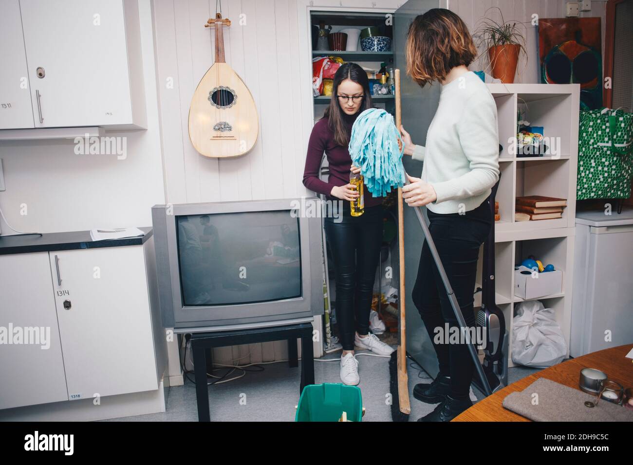 Jeune femme colocataire avec l'équipement de nettoyage debout près du placard dans dorm. collège Banque D'Images