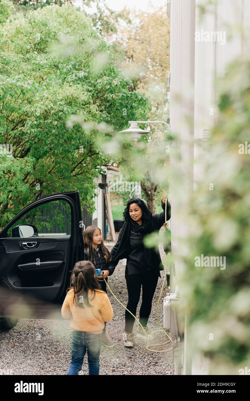 Femme avec des filles à la station de charge de voiture électrique Banque D'Images