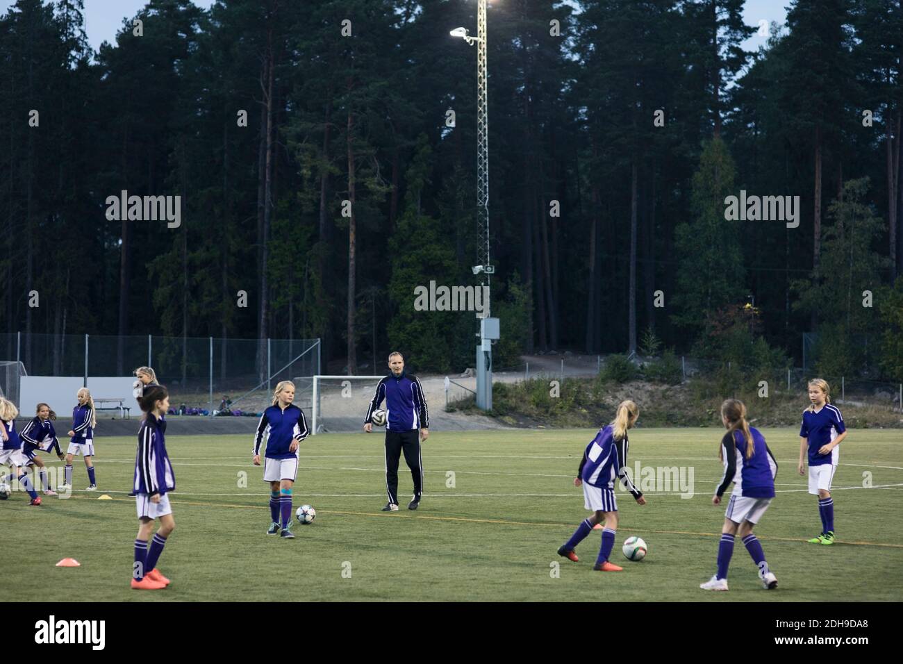 Coach regardant les filles jouant au football sur le terrain Banque D'Images