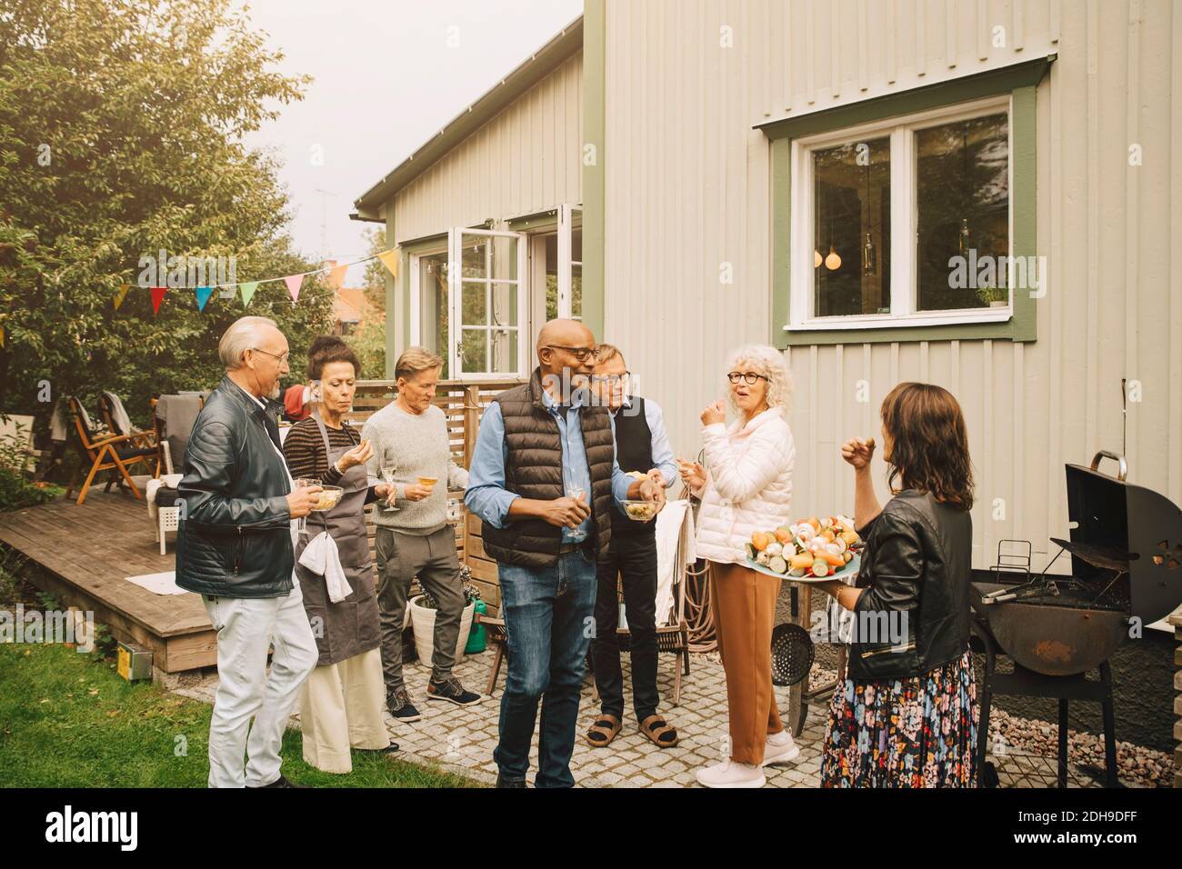 Des hommes et des femmes âgés actifs qui apprécient le dîner dans le dos cour Banque D'Images
