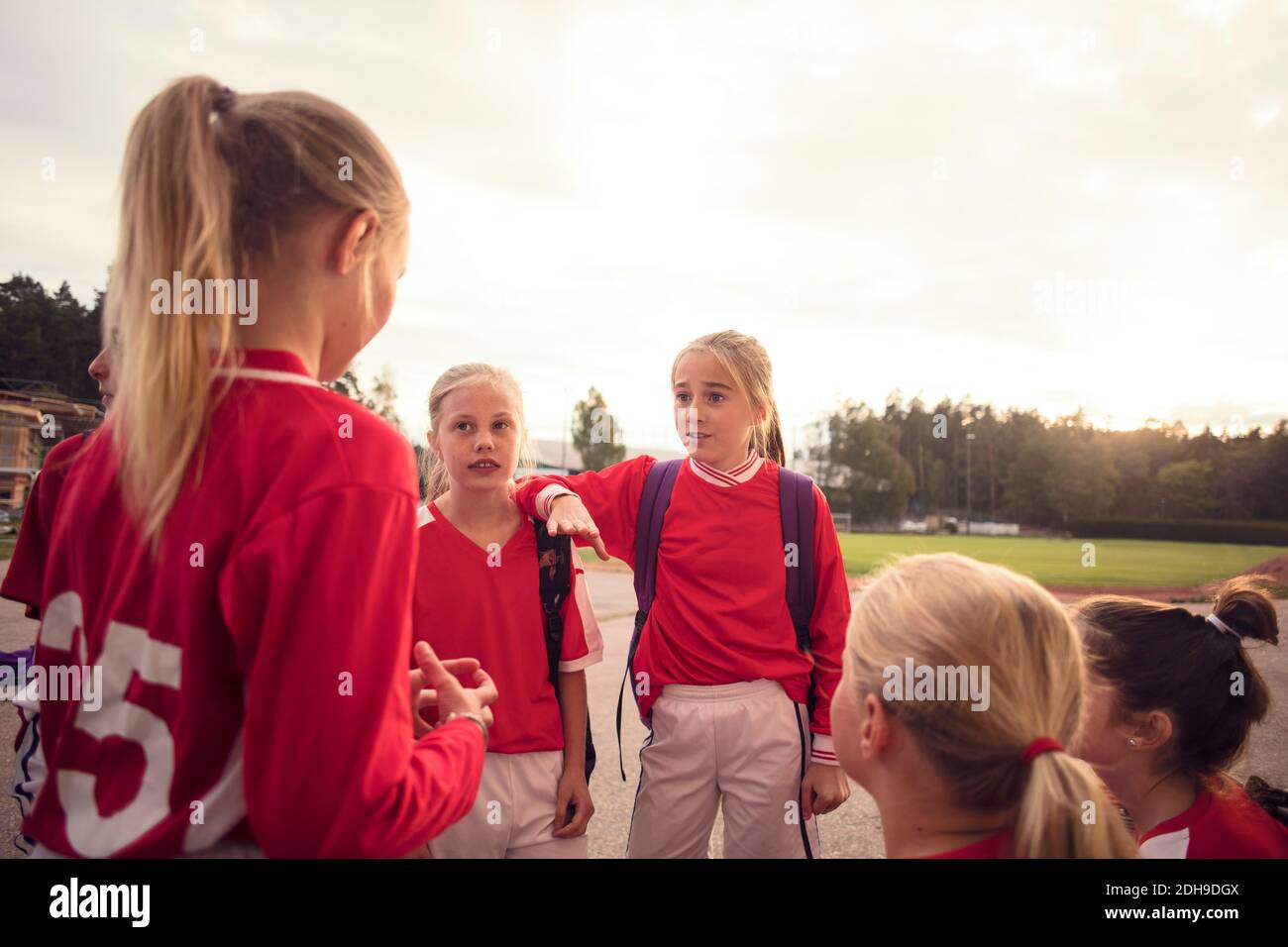 Les filles portent un uniforme de football rouge qui parle contre le ciel Banque D'Images