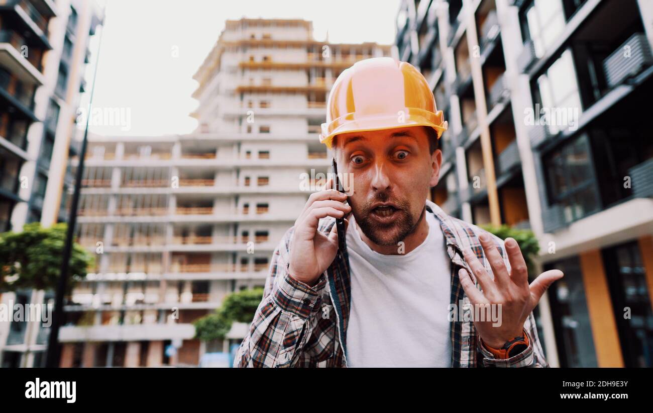 Ingénieur parlant au téléphone. Architecte utilisant le téléphone sur le chantier. Le contremaître du processus de contrôle des appels téléphoniques. Ouvrier de la construction c Banque D'Images