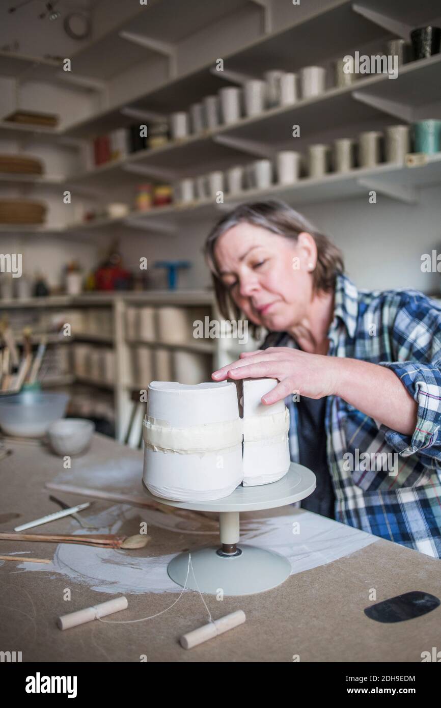Femelle mature potter travaillant à vase sur table dans l'atelier Banque D'Images