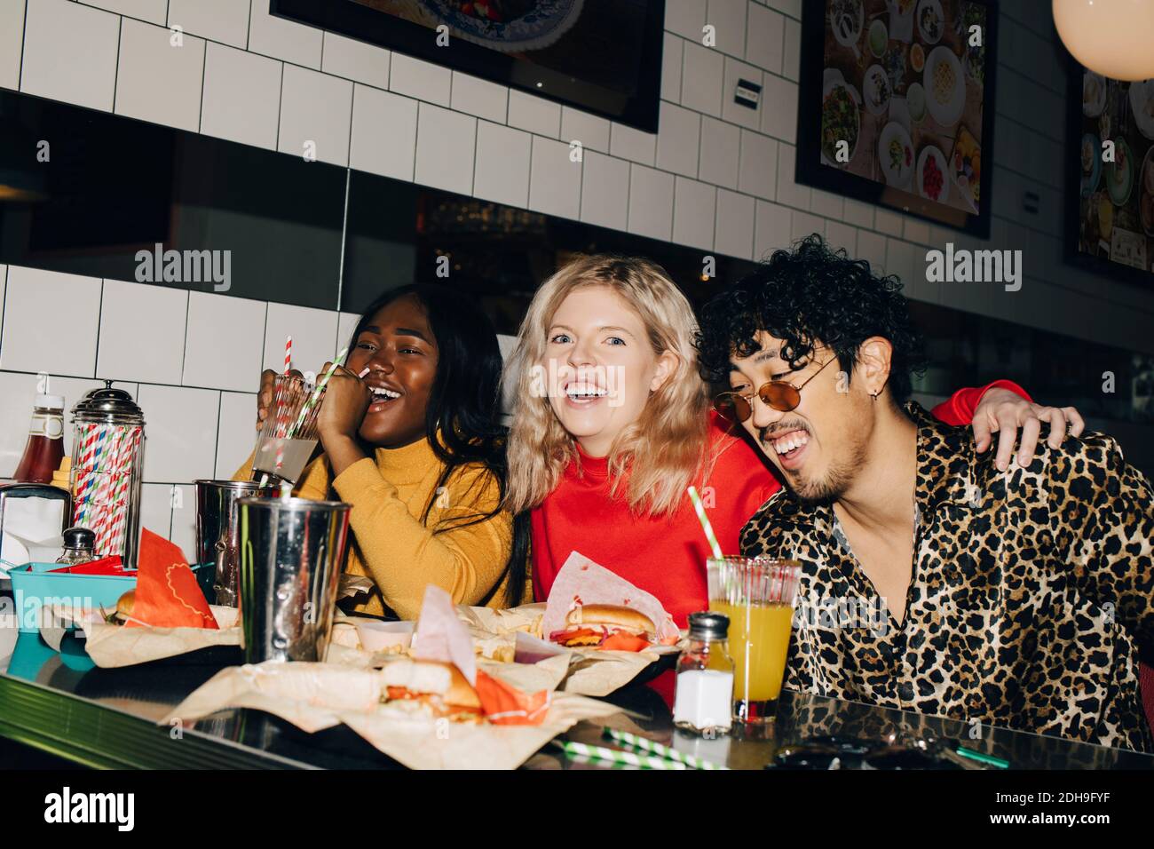 Portrait d'une femme heureuse avec des amis qui mangent du hamburger pendant la vie sociale rassemblement au café Banque D'Images