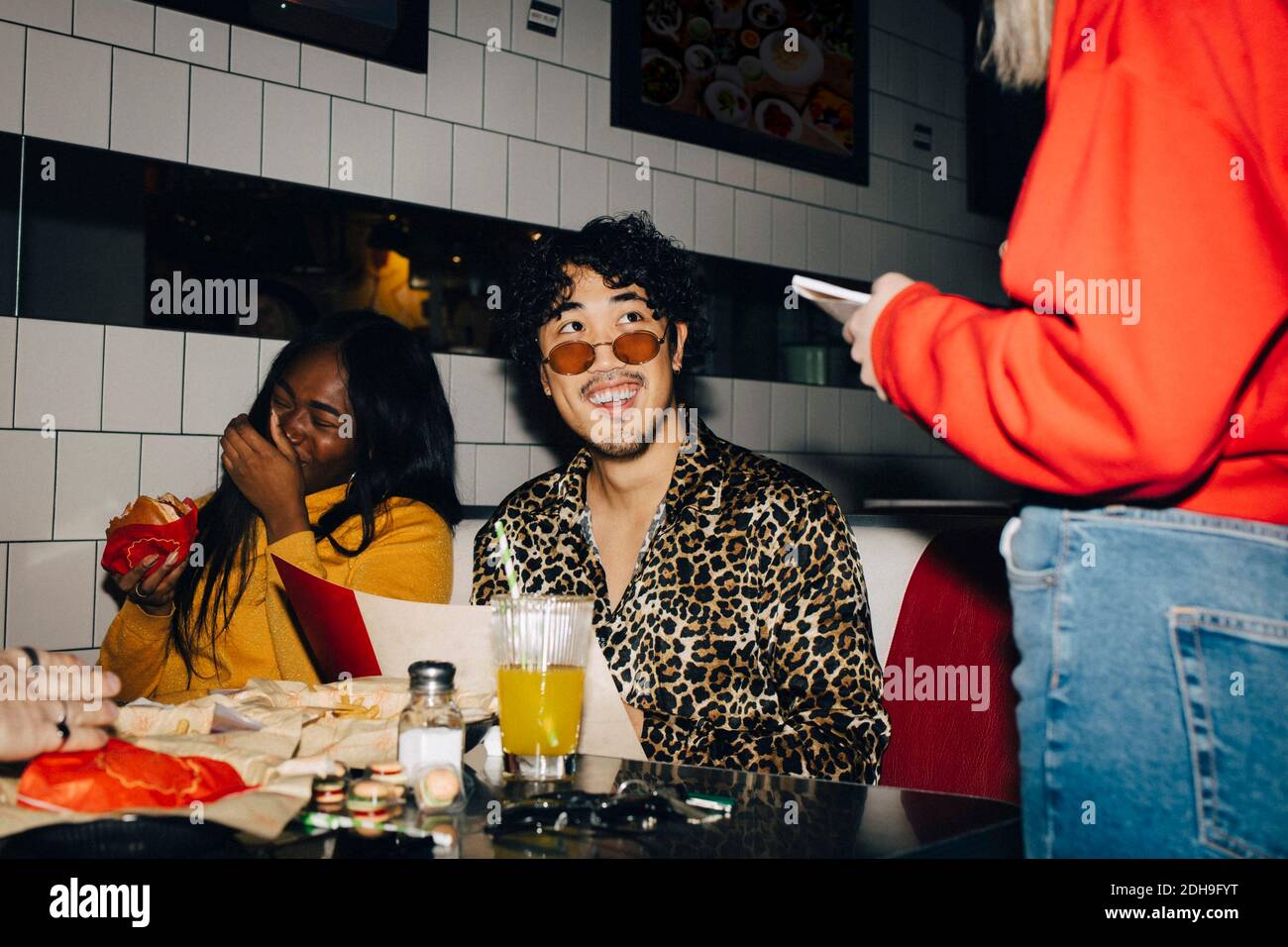 Milieu de la serveuse prenant commande de gai homme et femme amis au café Banque D'Images