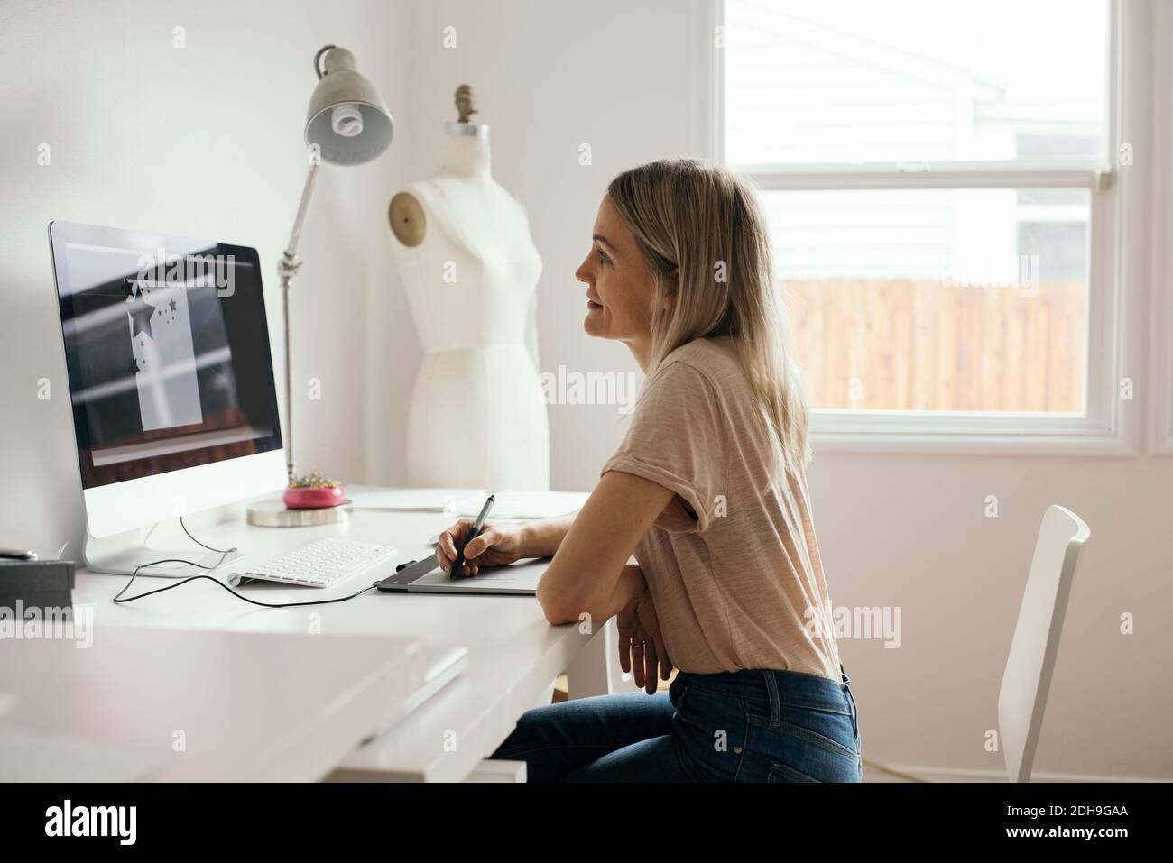 Vue latérale de la créatrice féminine à l'aide d'une tablette graphique à accueil Banque D'Images