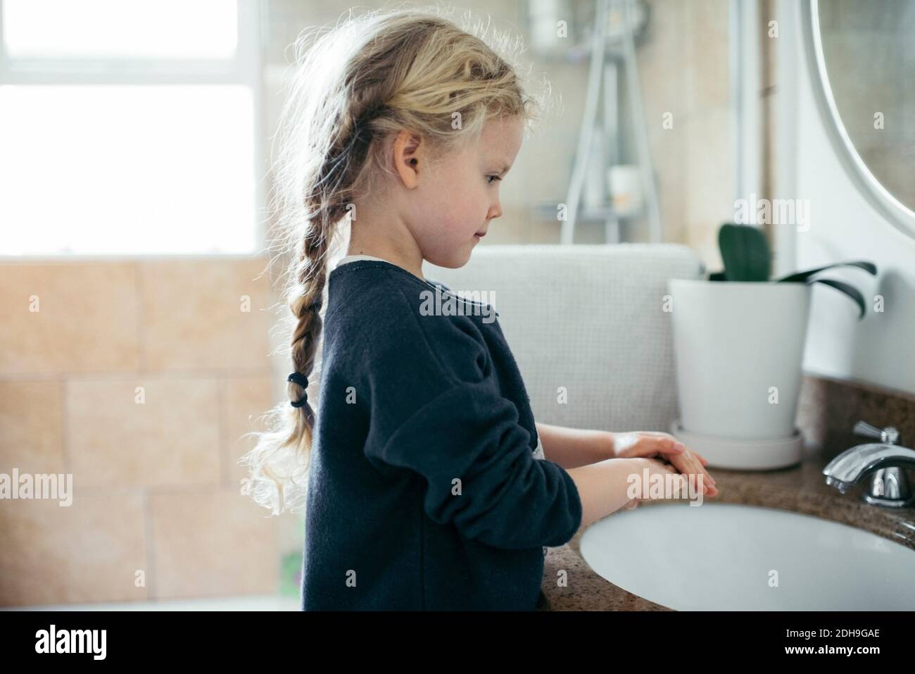 Vue latérale d'une fille se lavant les mains dans le lavabo de la salle de bains Banque D'Images