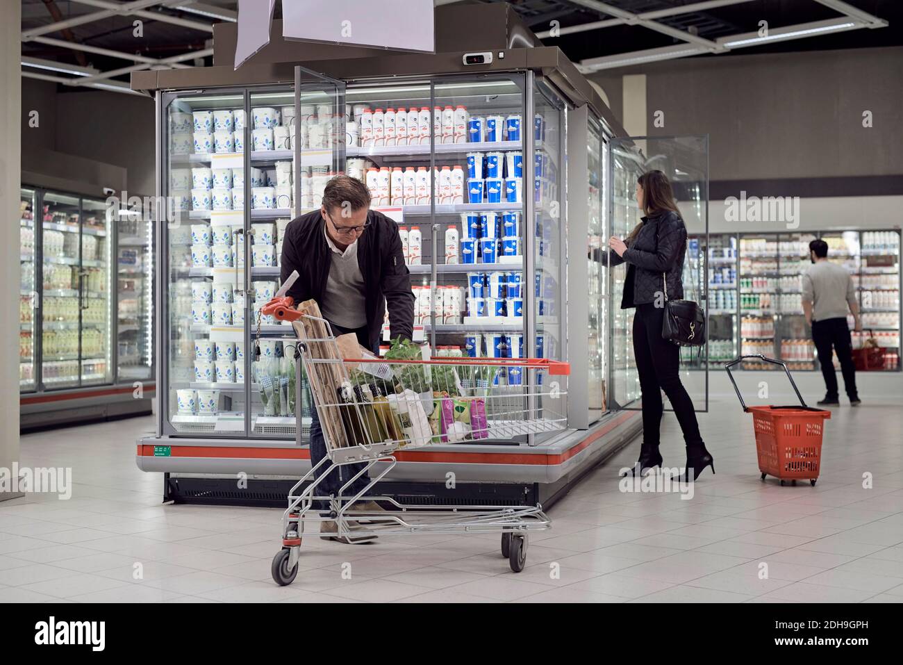 Les gens qui achètent des produits alimentaires à la section réfrigérée du supermarché Banque D'Images
