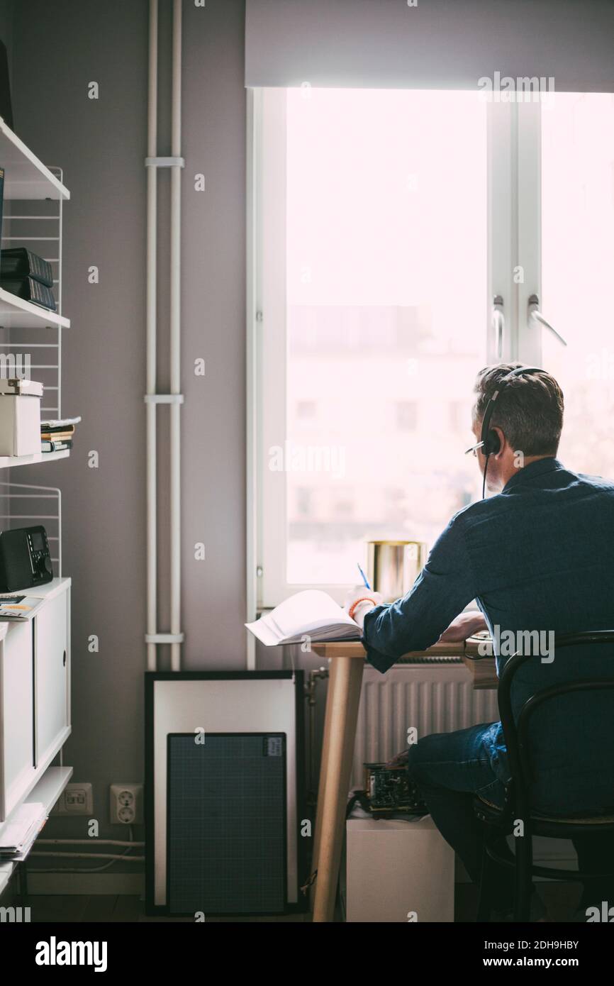 Vue arrière de l'homme dans le bureau à domicile ayant une conférence appeler Banque D'Images