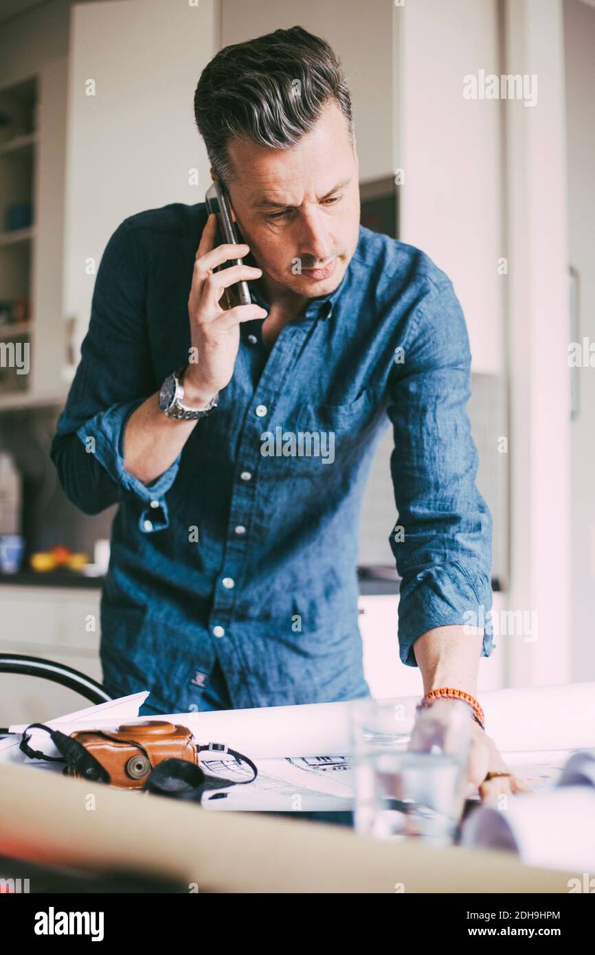 Homme au bureau à la maison parlant au téléphone Banque D'Images