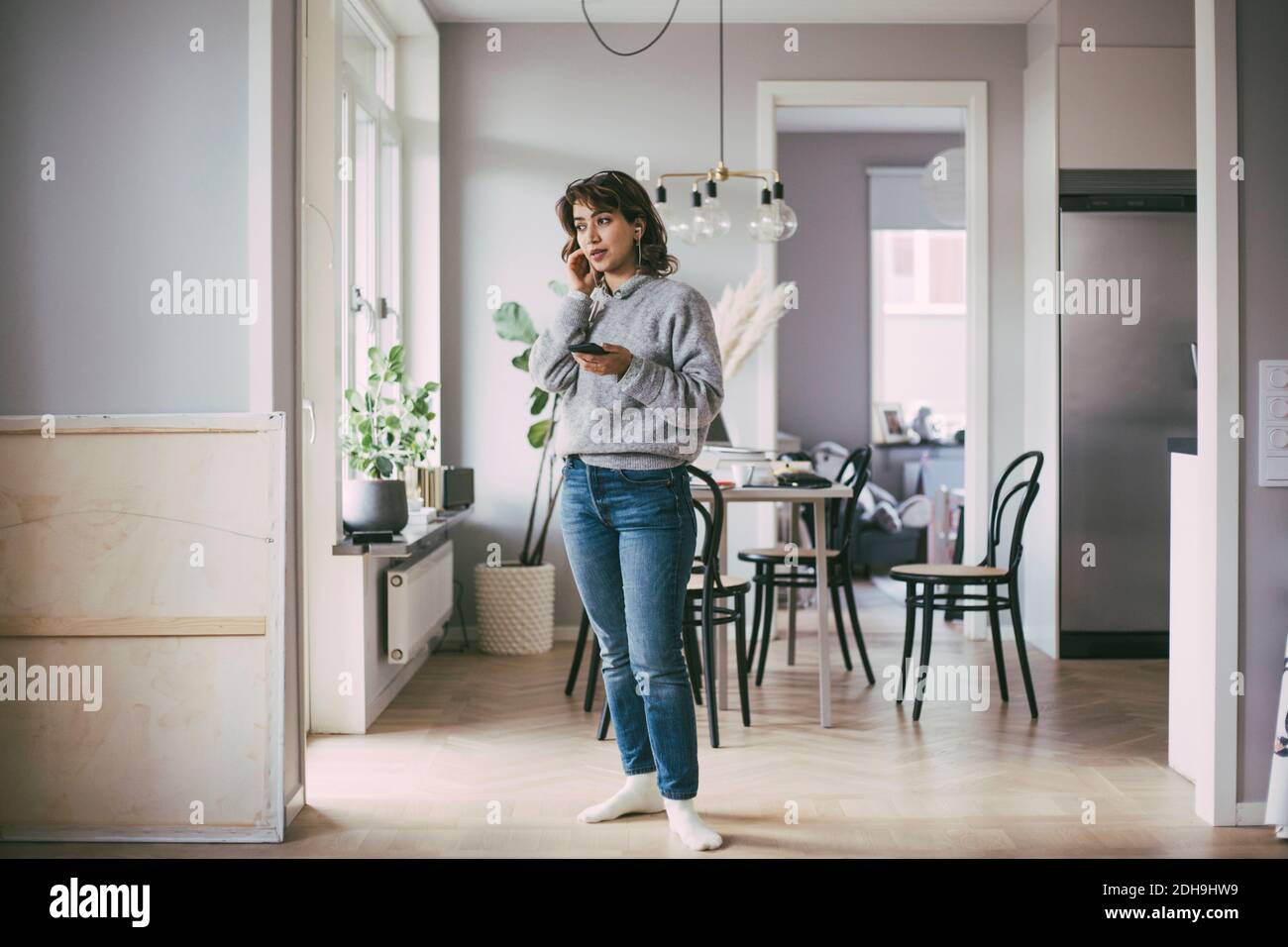 Femme debout à la maison parlant au téléphone Banque D'Images