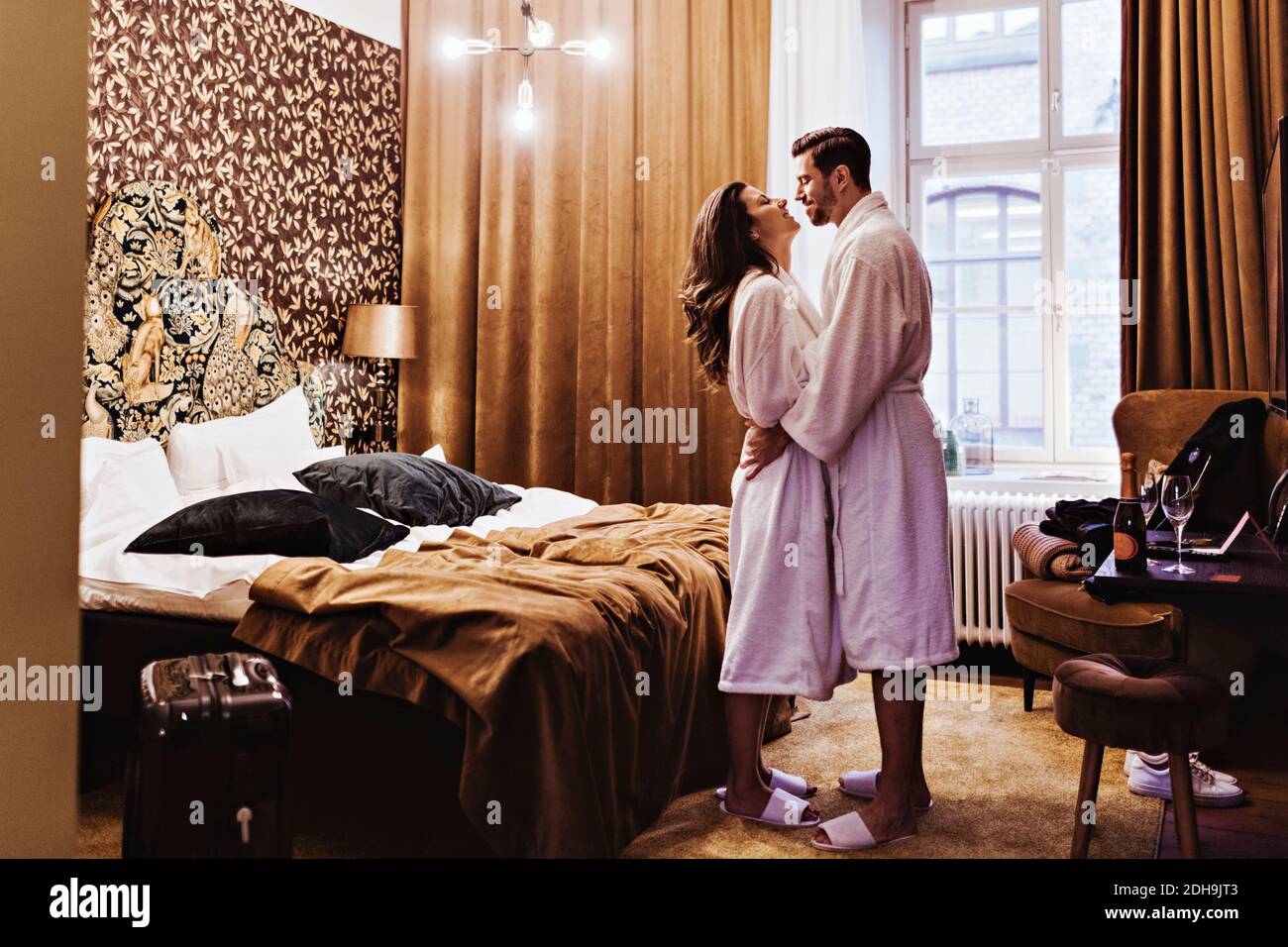 Vue latérale d'un couple romantique se tenant au lit dans la chambre  d'hôtel Photo Stock - Alamy