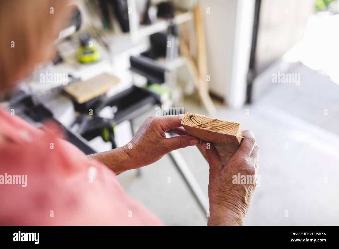 Image rognée d'une femme âgée tenant une planche en bois dans un atelier Banque D'Images