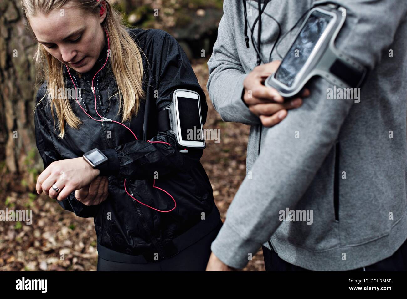 Athlètes masculins et féminins portant une montre intelligente et un bracelet en forêt Banque D'Images