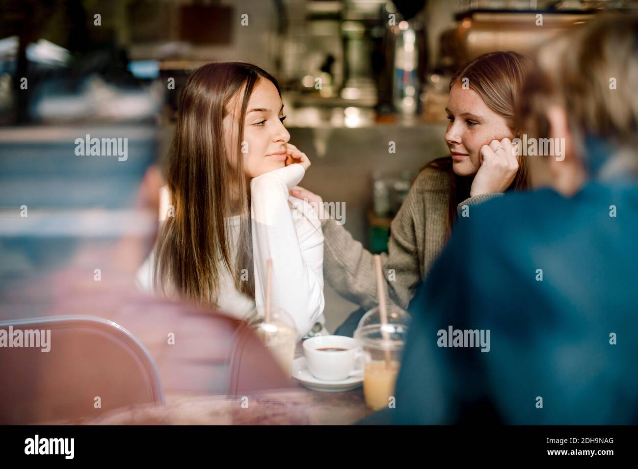 Adolescente regardant un ami assis dans un café Banque D'Images