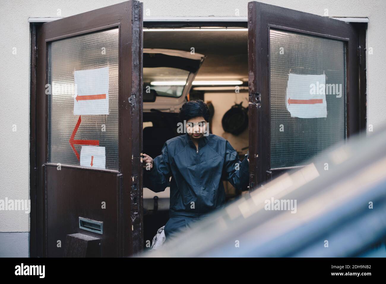 Une mécanicien d'automobiles ouvre les portes de l'atelier de réparation Banque D'Images