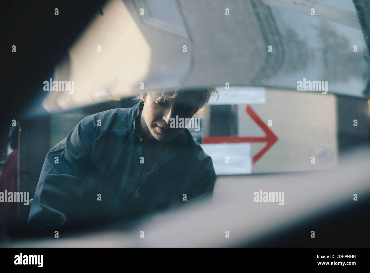 Femme mécanicien vue à travers le capot de voiture ouvert Banque D'Images