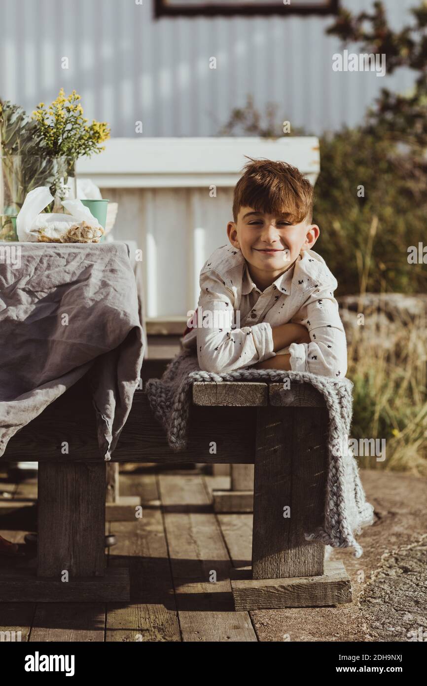 Portrait d'un garçon souriant allongé sur un siège en bois Banque D'Images