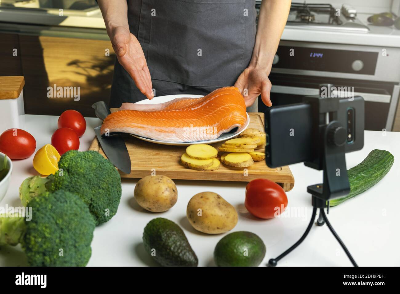 food blogger enregistrement vidéo à la cuisine maison avec téléphone. montrant la recette de préparation de saumon Banque D'Images