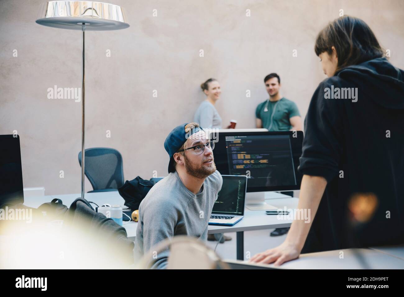 Les programmeurs d'ordinateurs hommes et femmes discutent dans le bureau créatif Banque D'Images