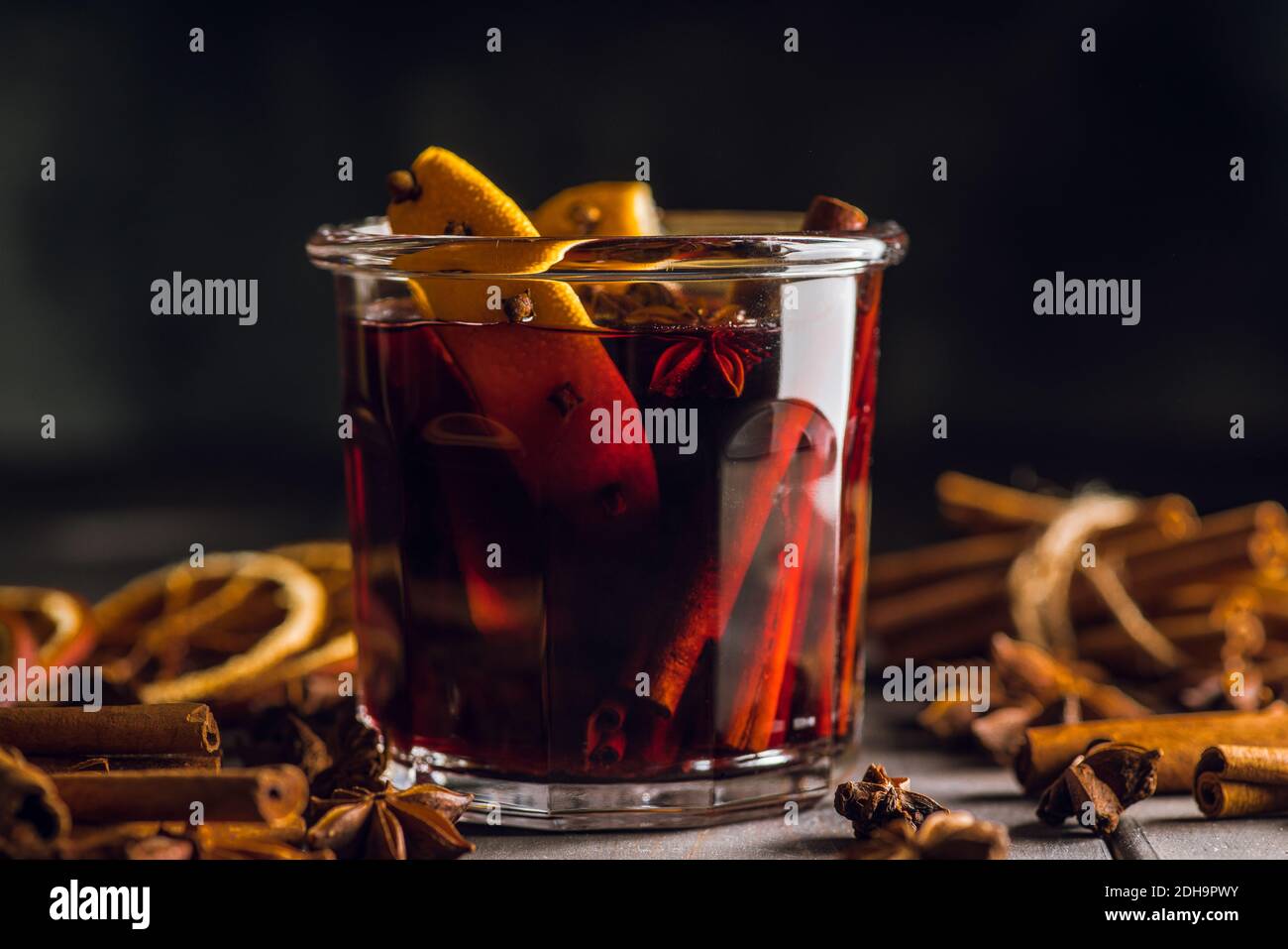 Vin rouge chaud accompagné d'oranges et de différentes épices en verre sur fond rustique. Repas de Noël. Décorations d'hiver. Mise au point sélective. Rayon peu profond Banque D'Images